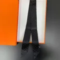 Dettaglio di un foulard in seta a pois neri in una confezione regalo arancione vivace - Stile a pois / Nero