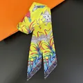 Macro detail of silk twilly scarf with yellow elephant and tropical plant prints - Yellow