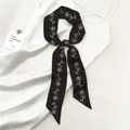 Dettaglio di un foulard nero con motivi di rose annodato a fiocco su tessuto di seta - Nero