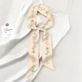 Dettaglio del twilly in seta con rose legato su un abito bianco per uno stile elegante - Beige