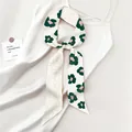 Dettaglio di un foulard twilly in seta floreale annodato su un abito con design double-face - Floreale Astratto Verde Scuro