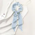 Dettaglio di un foulard in seta azzurro con motivo paisley annodato su un abito - Paisley Blu Chiaro