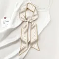 Dettaglio della sciarpa in seta twilly beige con motivo paisley su abito di raso - Paisley Beige Oro