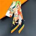 Detalle de pañuelo twilly con diseño de plumas en caja naranja y etiqueta de tela - Patchwork Tribal (C236-2)