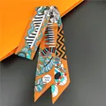 Detailed macro view of an orange silk twilly scarf with geometric patterns and fringe motif - Bright Orange Geometric Feather (C238-2)