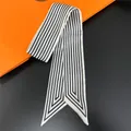 Detail of classic black and white striped silk twilly scarf on orange prop background - C241-1 / 90cm