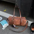 Brown suede-texture Boston bag with elegant pompom charm and long leather straps - With Pendant / Brown