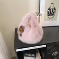 Borsa a mano rosa in ecopelliccia con ciondolo di peluche su mobiletto minimalista - Rosa