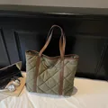 Bolso tote acolchado verde oscuro con asas de cuero marrón sobre cama blanca - Talla única / Verde