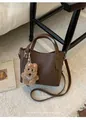 Detailed shot of brown lychee grain bucket bag with cute plush puppy charm and silver hardware - With Pendant / Brown