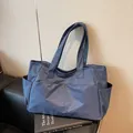 Borsa tote a scacchi blu scuro con tasche laterali su un divano in pelle nera - Taglia unica / Blu