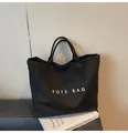 Detailansicht einer schwarzen Tragetasche mit weißem TOTE BAG Aufdruck und matter Textur - Einheitsgröße / Schwarz