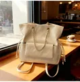 Quilted beige backpack with chain detail and drawstring in a cozy cafe window setting - One Size / White
