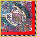 Macro detail of the paisley pattern on a red silk scarf with navy striped edges - Red
