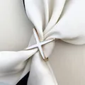 Detail einer goldenen Tuchbrosche mit weißem X-Design auf einem cremefarbenen Tuch - Weiße Emaille X / Gold