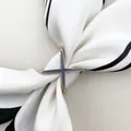 Macro detail of gold star silk scarf buckle featuring dark gray enamel on striped fabric - Gray Enamel X / Gold