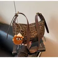 Detailansicht der Halbmond-Tasche mit Leopardenmuster, Plüsch-Anhänger und Ledergurt - Mit Anhänger / Kaffeebraun