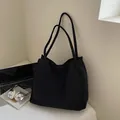 Minimalistische große schwarze Tragetasche mit Laptop und Kopfhörer auf Tisch - Schwarz