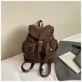 Detalle de mochila vintage marrón oscuro con dos bolsillos frontales y hebillas plata - Café