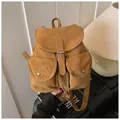 Detalle de una mochila vintage amarillo mostaza con textura mate y hebillas decorativas - Marrón