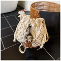 Detail of hand-woven cream bucket bag featuring intricate 3D floral patterns and a cute charm - With Pendant / Off White