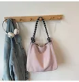 Pink corduroy crossbody bag with checkered rope handle hanging on a wooden hook - Pink