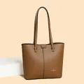 Detalle de la textura de cuero lichi caramelo y el logo de marca en el bolso tote - Talla única / Marrón