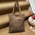 Bolso tote acolchado marrón oscuro con bolsillo frontal y asas sobre una escalera - Talla única / café