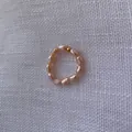 Makroaufnahme eines handgefertigten Perlenrings mit rosa Barockperlen und goldener Perle - Elastischer Perlenstil / Standardgröße / Hellrosa