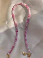 Detail van roze en paarse natuurstenen kralen met gouden karabijnsluiting en logo-label - Ketting / 38+5cm / Roze Paars