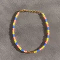 Détail d'un bracelet en perles colorées avec carrés dorés et fermoir mousqueton - Style de perles facettées orange jaune bleu et perles de séparation dorées / Taille unique / 17+3cm / Multicolore