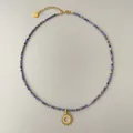 Detalle del collar de cuentas azul oscuro con colgante de sol dorado y dije de corazón - Estilo Colgante Sol de Cuentas Azules