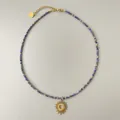 Detalle macro del collar de cuentas naturales con colgante de sol y cierre de corazón - Estilo Colgante Sol Corazón de Cuentas Azules