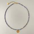 Detalle de collar de piedras azules con colgante de sol dorado y cadena de extensión - Estilo Colgante Disco Redondo de Cuentas Azules