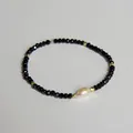 Gros plan d'un bracelet de perles noires à facettes avec une perle goutte blanche et dorure - Style perle noire facettée (Style 1A)