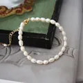 Detail van natuurlijke zoetwaterparel armband met gouden sluiting op vintage dienblad - Armband Stijl E (17+3cm)
