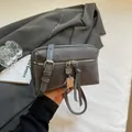Gray suede crossbody bag with a robot charm and silver zipper shown in hand - Gray
