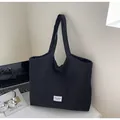 Dettaglio della borsa tote in tela nera a pieghe con etichetta su una scrivania - Nero