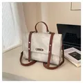 Vintage beige messenger bag with brown leather straps and metal rivets on office desk - Rice White - With Charms / Off White
