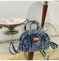 Detail view of denim pillow bag with acid wash texture, leather label and silver hardware - One Size / Blue