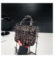 Detail van luipaardprint tote bag met zilveren studs, kruishanger en metalen kettingaccent - Bruin