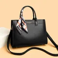 Details einer schwarzen Leder-Tote-Bag mit Seidenschal und Metall-Schutzfüßen - Schwarz