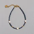 Gedetailleerd macrobeeld van kralenarmband met blauwe stenen en een hartvormig label - Donkerblauwe Gefacetteerde Stijl