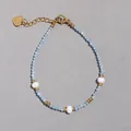 Dettaglio macro del bracciale con perle d'acqua dolce, pietre blu e ciondolo a cuore - Stile Sfaccettato Blu Chiaro