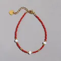 Dettaglio di bracciale con pietre rosse sfaccettate, perle e ciondolo a cuore dorato - Stile Minerale Sfaccettato Rosso