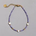 Macro scatto di braccialetto di perle viola con accenti dorati e perle barocche - Stile Taglio Sfaccettato Minerale Viola