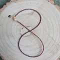 Detail of thin garnet bead necklace with gold lobster clasp and heart charm on wood - Deep Red Faceted Garnet (F) / 38cm+5cm