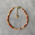 Handgemaakte kralenarmband met gefacetteerde rode agaatstenen en een gouden hartbedeltje - Gefacetteerde warme natuursteen stijl / Eén maat / 17+3cm / Warm Oranje