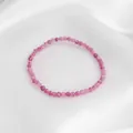 Détail des perles facettées en quartz fraise rose posées sur un tissu en soie élégant - Style de perles micro-facettées roses / Taille unique / Corde Élastique 16cm / Rose