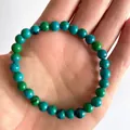 Macro-opname van een elastische armband met blauw-groene natuurstenen op een hand - Blauw-Groene Textuur(Armband 11)